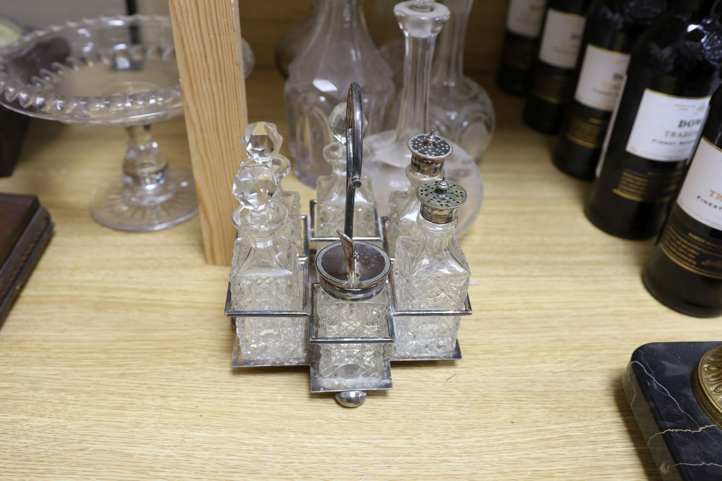 Sundry glassware including a six bottle cruet set on a plated stand, a Victorian cut glass jug, a pair of long neck decanters, five other decanters and a glass cake tazza